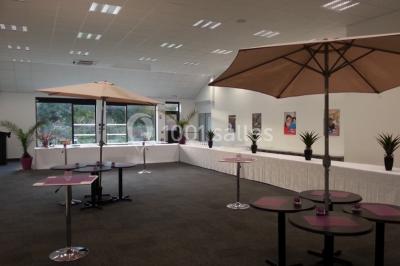 Table décorée avec un vase, des pétales rouges et des plantes en pot dans une salle lumineuse.