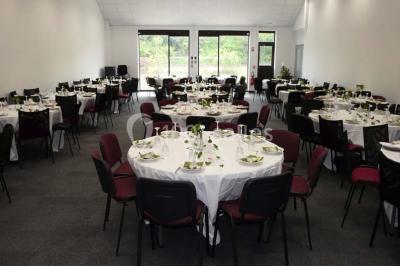Table décorée avec un vase, des pétales rouges et des plantes en pot dans une salle lumineuse.