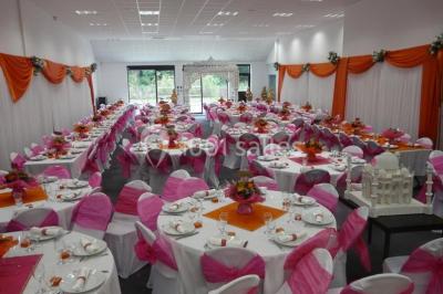 Table décorée avec un vase, des pétales rouges et des plantes en pot dans une salle lumineuse.