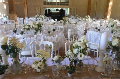 Serre illuminée au crépuscule, entourée de murs en pierre et d'arbres, avec une tour en arrière-plan.