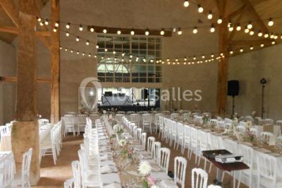 Serre illuminée au crépuscule, entourée de murs en pierre et d'arbres, avec une tour en arrière-plan.