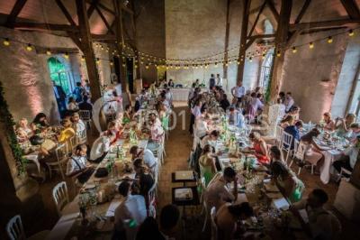 Serre illuminée au crépuscule, entourée de murs en pierre et d'arbres, avec une tour en arrière-plan.