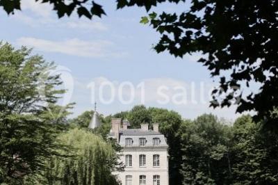 Serre illuminée au crépuscule, entourée de murs en pierre et d'arbres, avec une tour en arrière-plan.
