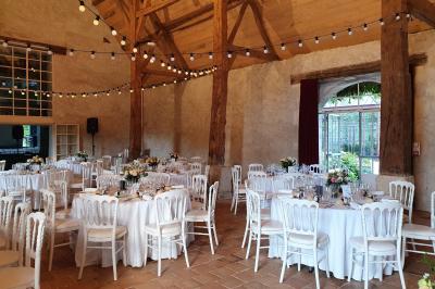 Serre illuminée au crépuscule, entourée de murs en pierre et d'arbres, avec une tour en arrière-plan.