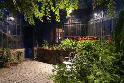 Serre illuminée au crépuscule, entourée de murs en pierre et d'arbres, avec une tour en arrière-plan.