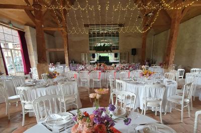 Serre illuminée au crépuscule, entourée de murs en pierre et d'arbres, avec une tour en arrière-plan.