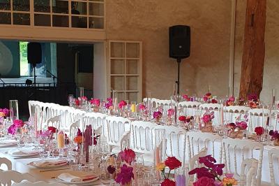 Serre illuminée au crépuscule, entourée de murs en pierre et d'arbres, avec une tour en arrière-plan.