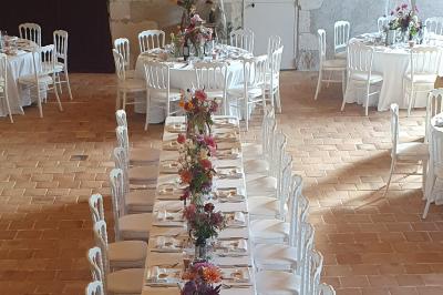 Serre illuminée au crépuscule, entourée de murs en pierre et d'arbres, avec une tour en arrière-plan.