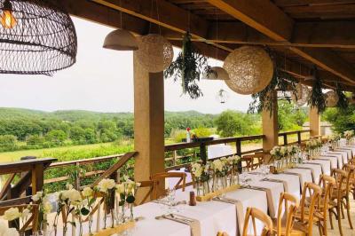 Bâtisse en pierre avec toit en tuiles, entourée de végétation et d'un chemin sous un ciel bleu clair.