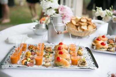 Bâtisse en pierre avec toit en tuiles, entourée de végétation et d'un chemin sous un ciel bleu clair.