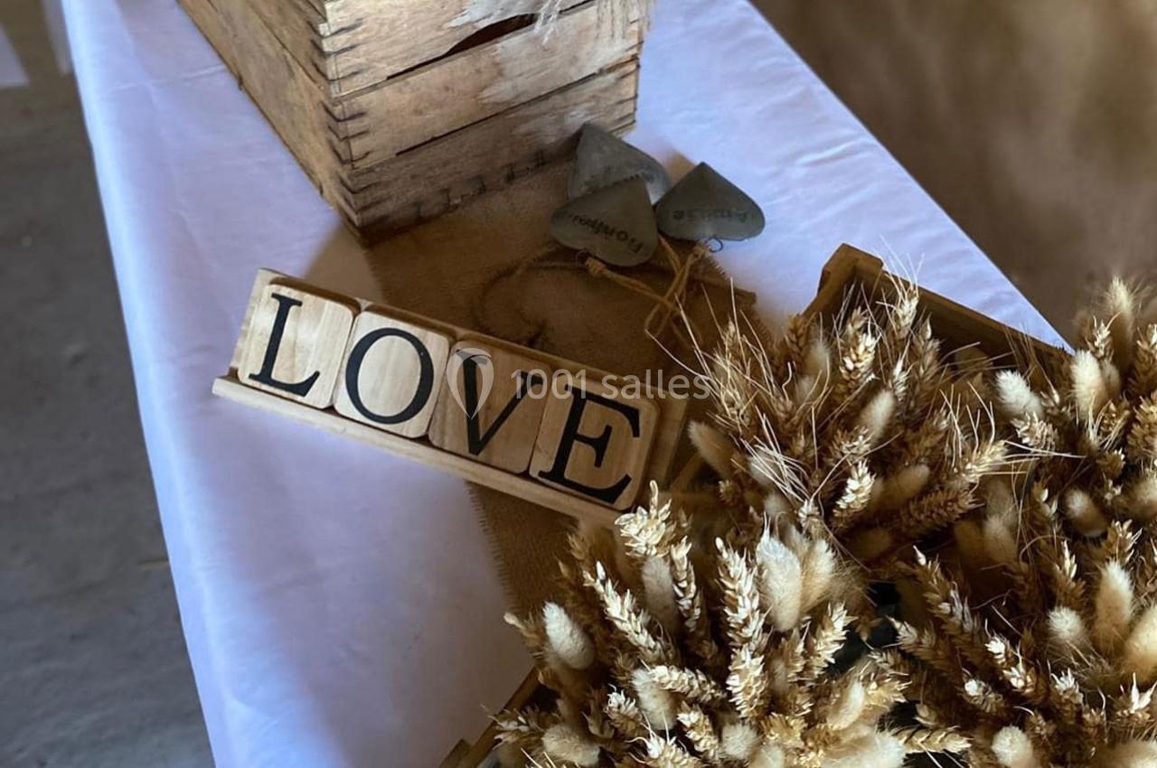 Décoration de table avec un panneau ’LOVE’, des bouquets de fleurs séchées et une caisse en bois rustique.