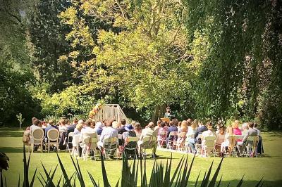 Un vélo ancien posé près de caisses en bois et d'objets décoratifs dans un jardin verdoyant.