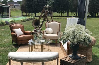 Un vélo ancien posé près de caisses en bois et d'objets décoratifs dans un jardin verdoyant.