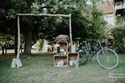 Un vélo ancien posé près de caisses en bois et d'objets décoratifs dans un jardin verdoyant.