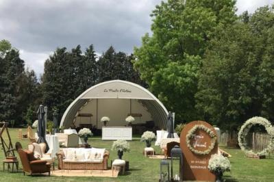 Un vélo ancien posé près de caisses en bois et d'objets décoratifs dans un jardin verdoyant.
