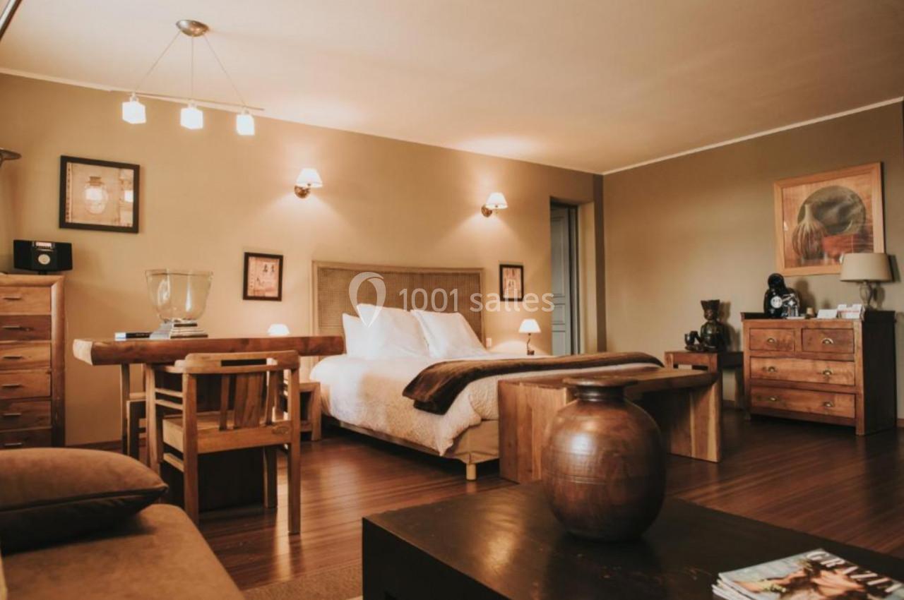 Chambre chaleureuse avec lit double, mobilier en bois, éclairage doux et décoration murale.