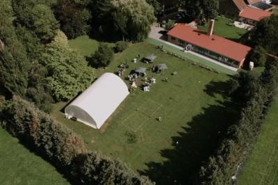 Un vélo ancien posé près de caisses en bois et d'objets décoratifs dans un jardin verdoyant.