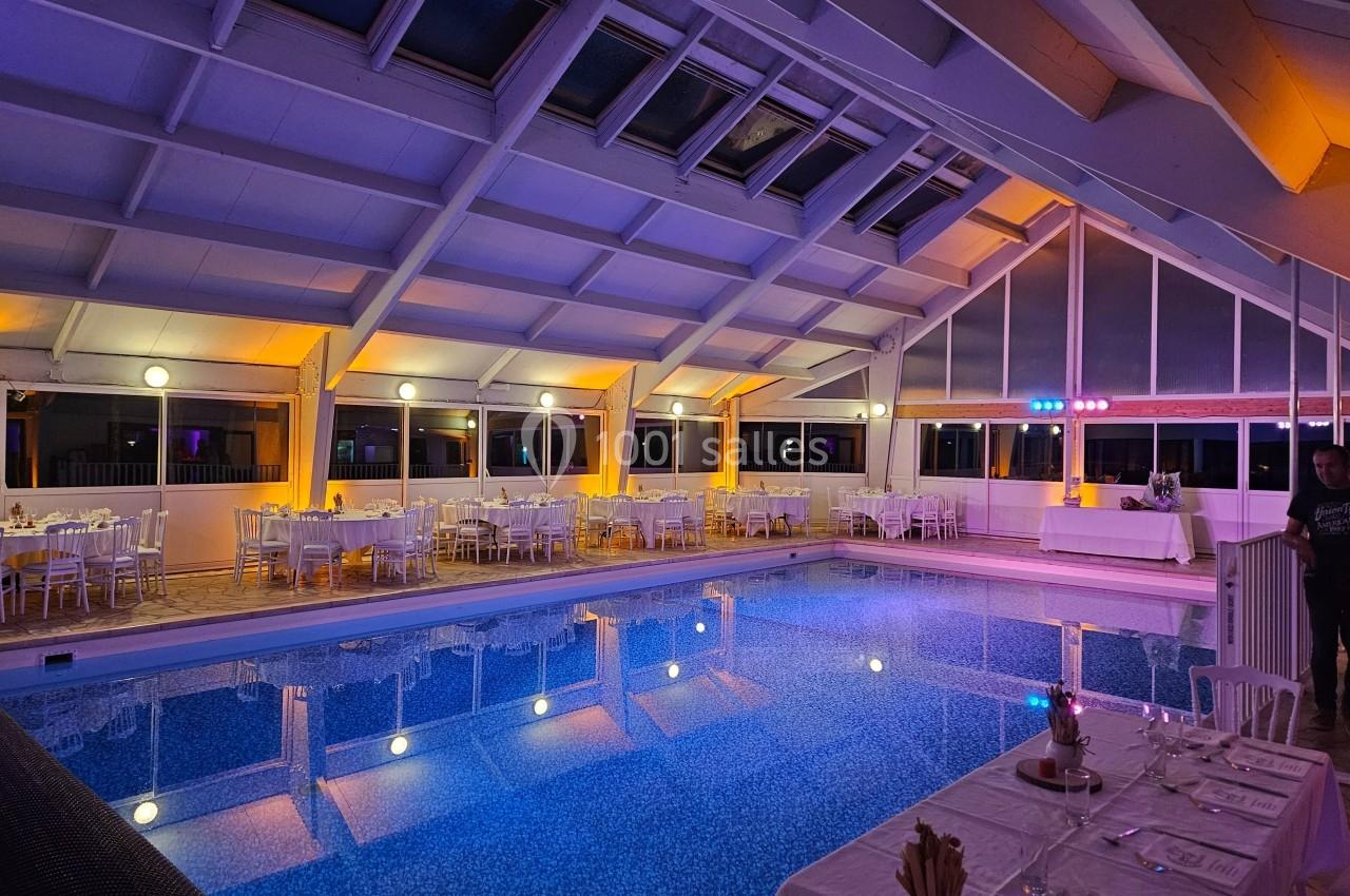 Piscine intérieure éclairée avec des tables dressées autour pour un événement dans une ambiance chaleureuse.