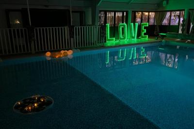 Table de buffet décorée de pampas, éclairée par des lumières violettes, avec plats et condiments disposés.