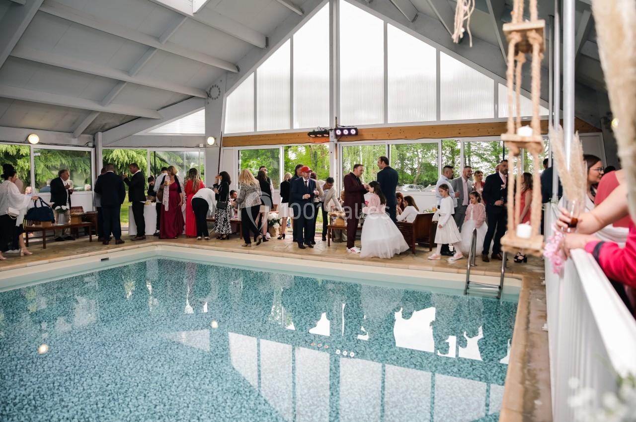 Groupe de personnes rassemblées près d'une piscine intérieure lors d'un événement festif.