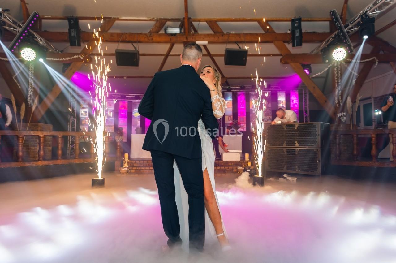 Un couple danse au milieu d'une piste entourée d'effets lumineux et de jets d'étincelles.