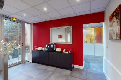 Salle de réunion avec une longue table rectangulaire, chaises noires, projecteur et murs blancs et rouges.