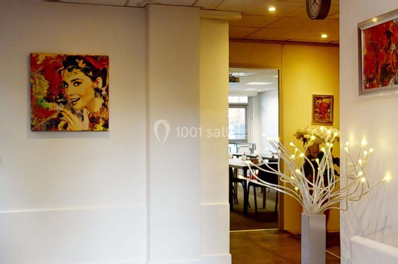 Vue d'un intérieur lumineux avec des tableaux colorés accrochés aux murs et un vase décoratif avec des lumières.