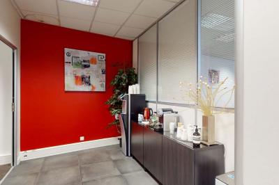 Salle de réunion avec une longue table rectangulaire, chaises noires, projecteur et murs blancs et rouges.