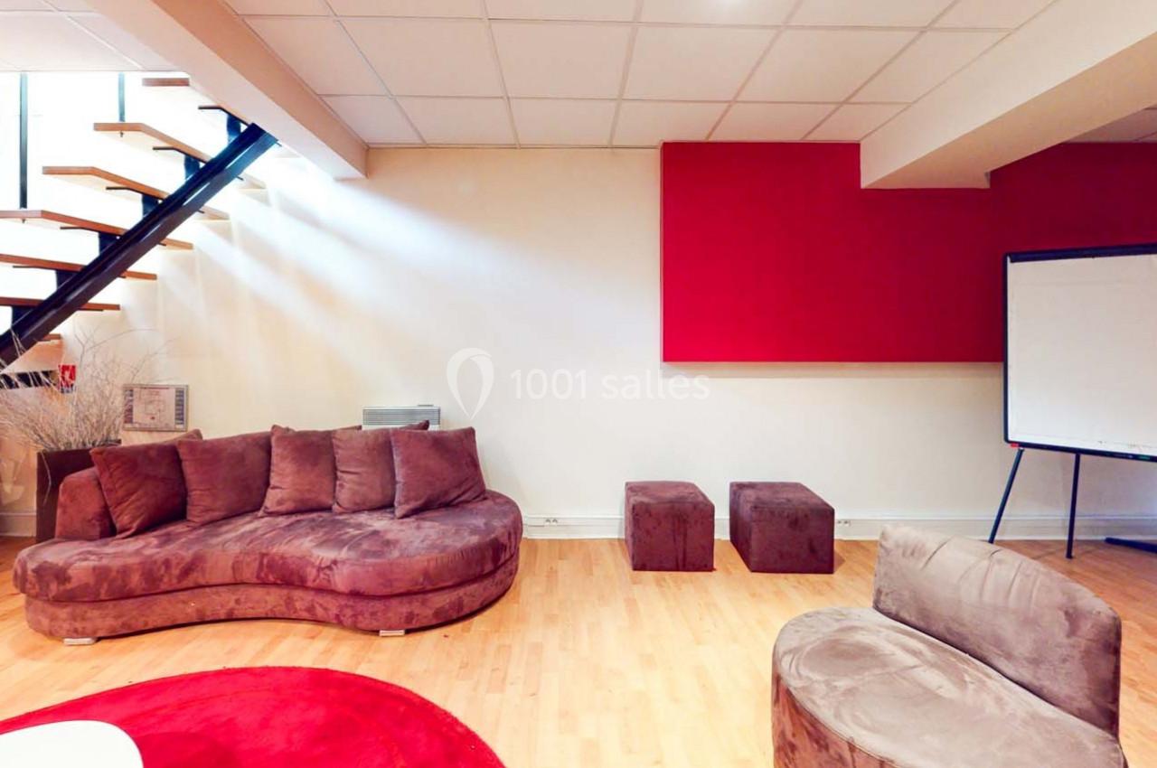 Espace intérieur avec canapé en velours marron, escalier moderne, tableau blanc et décoration minimaliste.