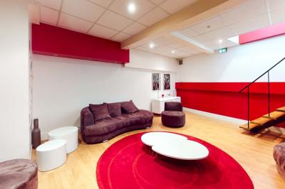 Salle de réunion avec une longue table rectangulaire, chaises noires, projecteur et murs blancs et rouges.