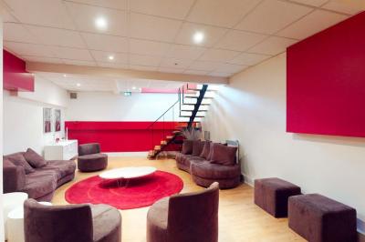Salle de réunion avec une longue table rectangulaire, chaises noires, projecteur et murs blancs et rouges.