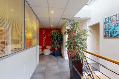 Salle de réunion avec une longue table rectangulaire, chaises noires, projecteur et murs blancs et rouges.