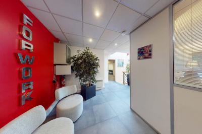 Salle de réunion avec une longue table rectangulaire, chaises noires, projecteur et murs blancs et rouges.