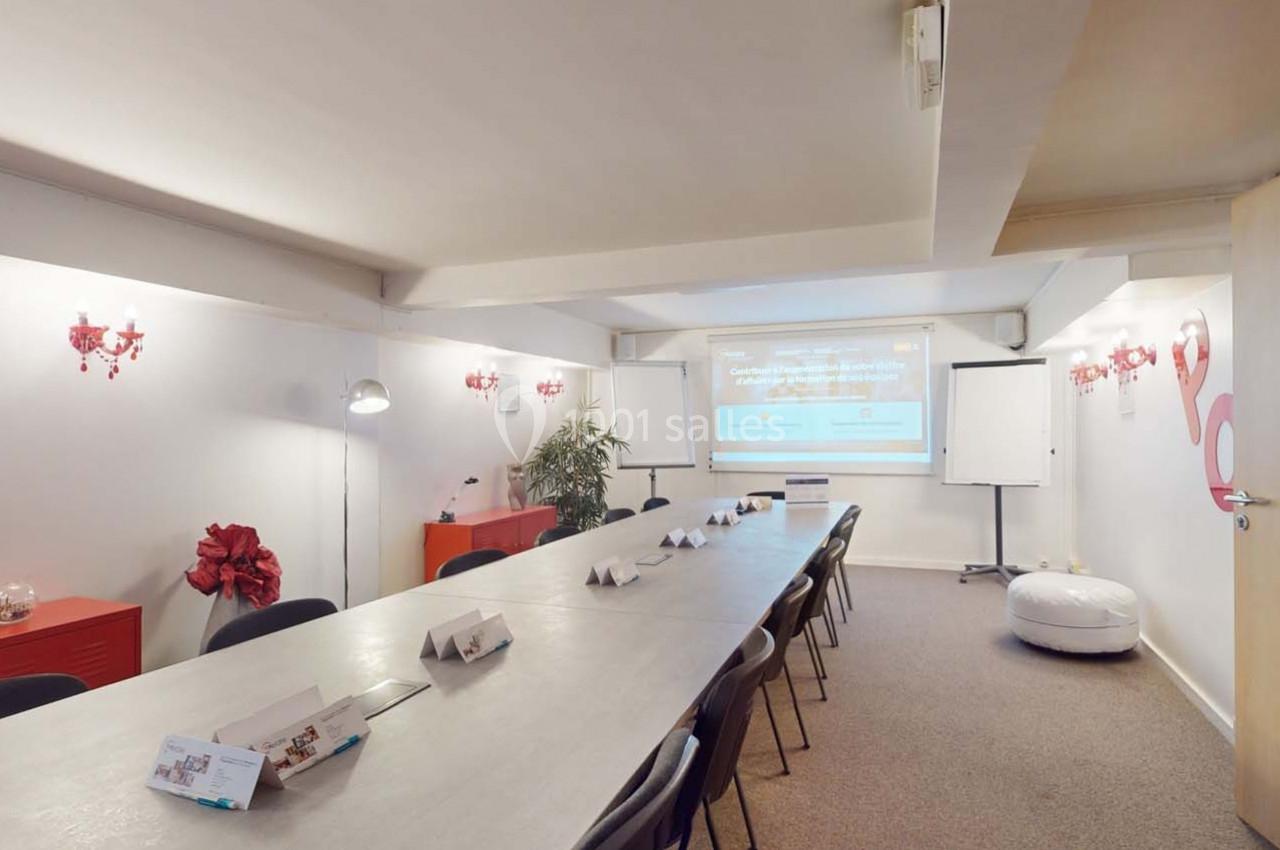 Salle de réunion lumineuse avec une longue table, des chaises, un vidéoprojecteur, un tableau blanc et des décorations…