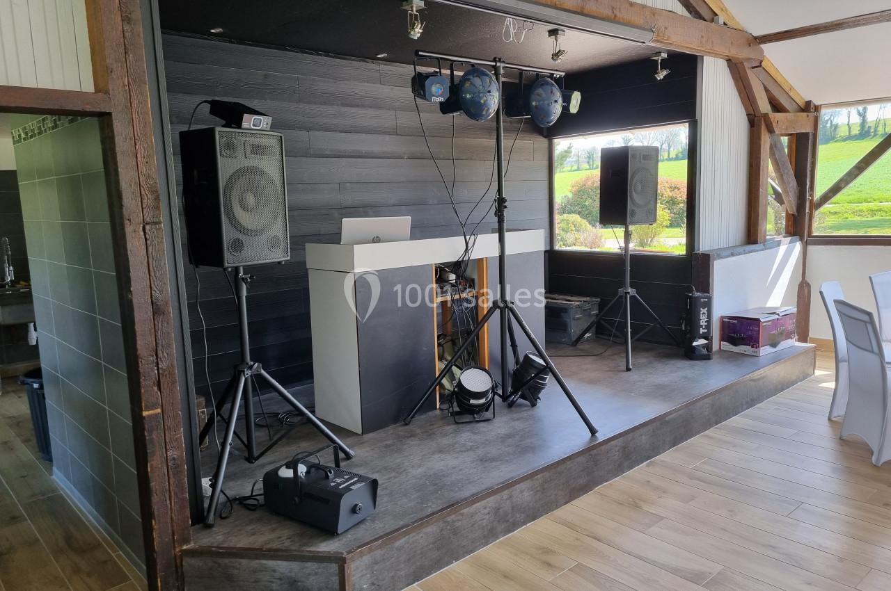 Installation de matériel de sonorisation et d'éclairage sur une petite scène en bois dans une salle lumineuse.