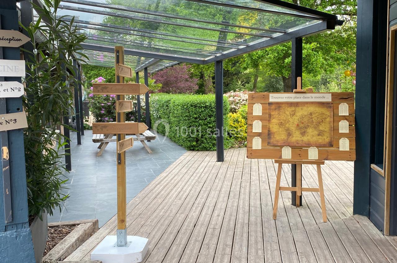 Panneau directionnel en bois et tableau d'affichage sur une terrasse en bois entourée de végétation.