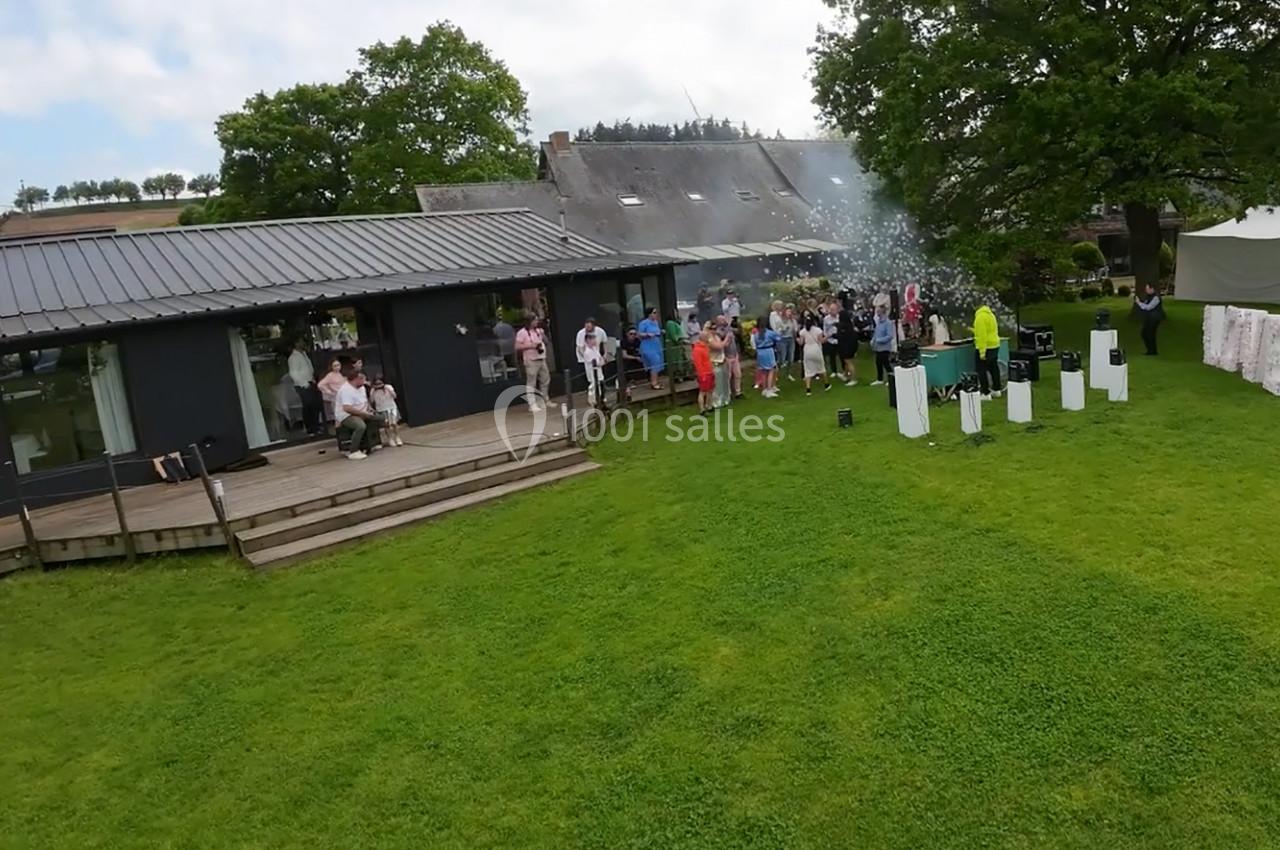 Un groupe de personnes rassemblées sur une pelouse près d'un bâtiment moderne, avec des fumées en arrière-plan.
