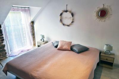 Chambre lumineuse avec un lit double, couvre-lit rose, deux tables de chevet et une décoration murale.