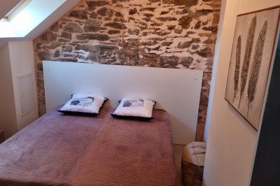 Chambre lumineuse avec un lit double, couvre-lit rose, deux tables de chevet et une décoration murale.