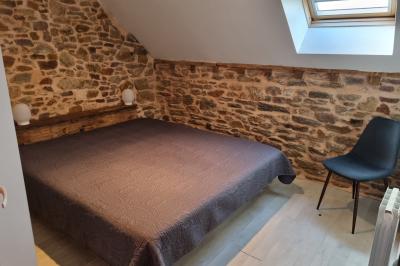 Chambre lumineuse avec un lit double, couvre-lit rose, deux tables de chevet et une décoration murale.