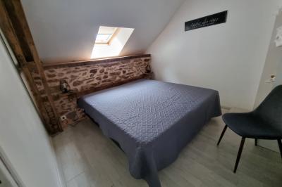 Chambre lumineuse avec un lit double, couvre-lit rose, deux tables de chevet et une décoration murale.