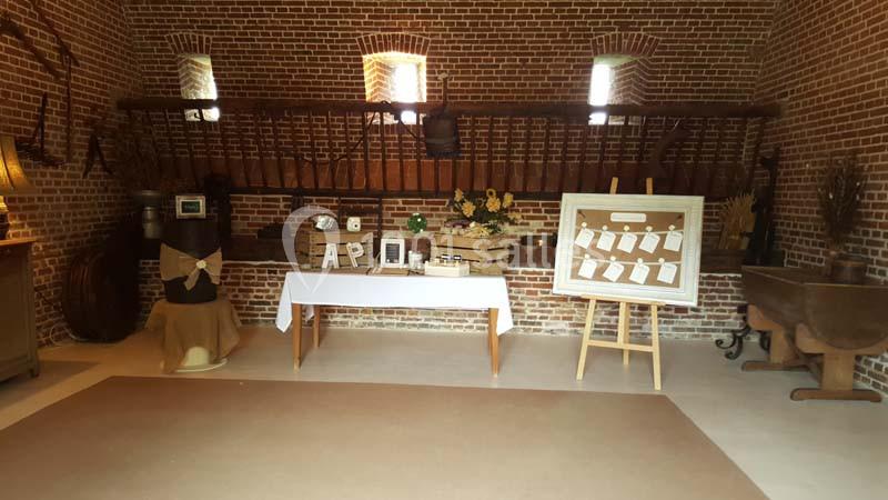 Salle en briques aménagée avec des décorations rustiques, une table blanche et un tableau d'affichage en bois.