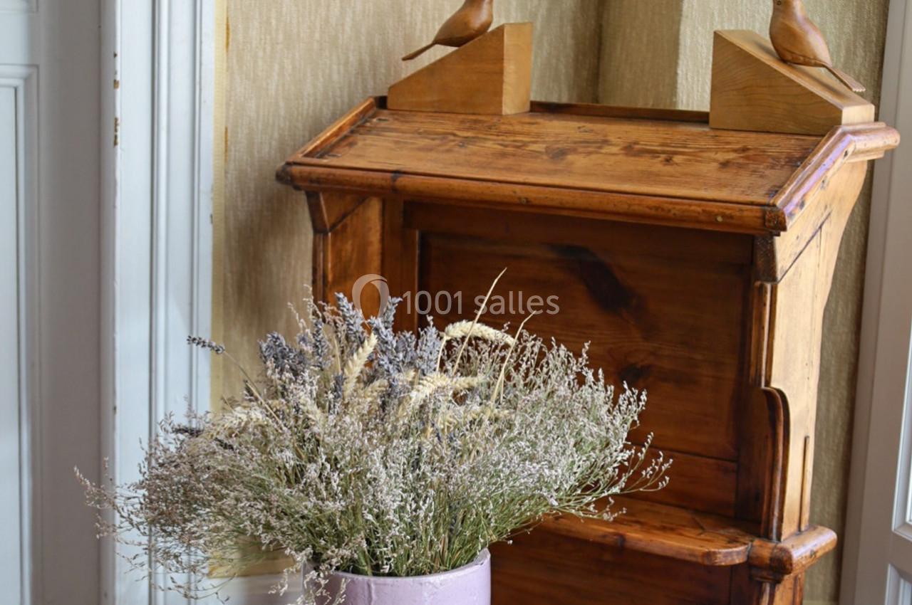 Commode en bois avec deux sculptures d'oiseaux, accompagnée d'un vase de fleurs séchées dans un intérieur lumineux.