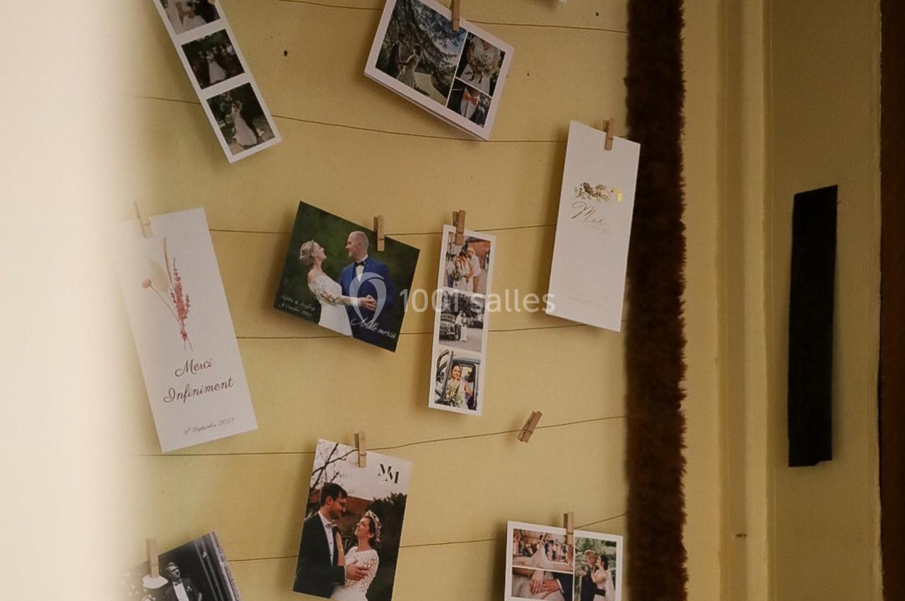 Photos de mariage et cartes accrochées à des fils tendus sur un mur beige avec des pinces en bois.
