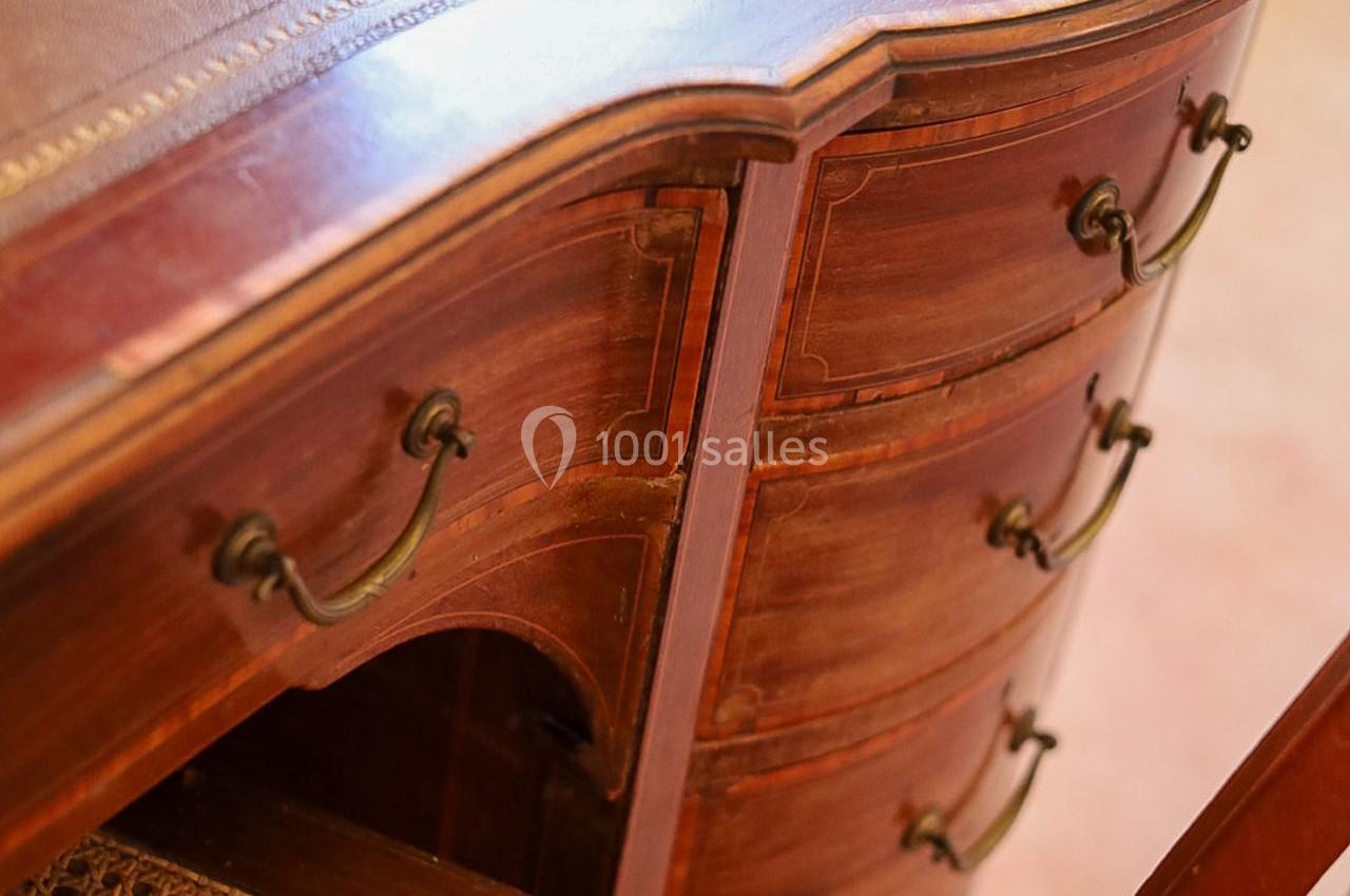 Commode en bois verni avec tiroirs incurvés et poignées métalliques, détail d'un meuble ancien.