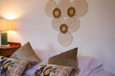 Lit avec coussins colorés et décoration murale en macramé dans une chambre lumineuse.