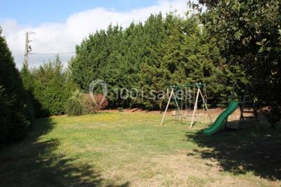 Lit double avec une couette blanche dans une chambre mansardée aux murs en pierre et plafond en bois.