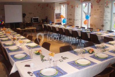 Lit double avec une couette blanche dans une chambre mansardée aux murs en pierre et plafond en bois.