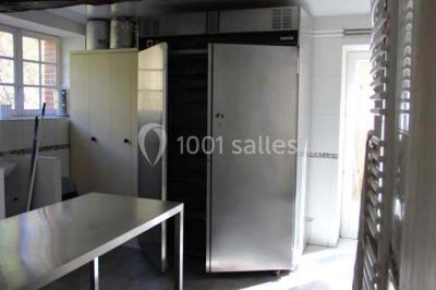 Lit double avec une couette blanche dans une chambre mansardée aux murs en pierre et plafond en bois.