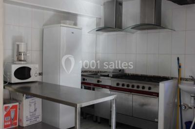 Lit double avec une couette blanche dans une chambre mansardée aux murs en pierre et plafond en bois.